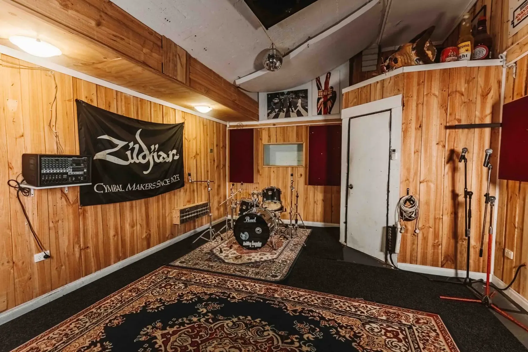 A timber-lined rehearsal room with drum kit and PA